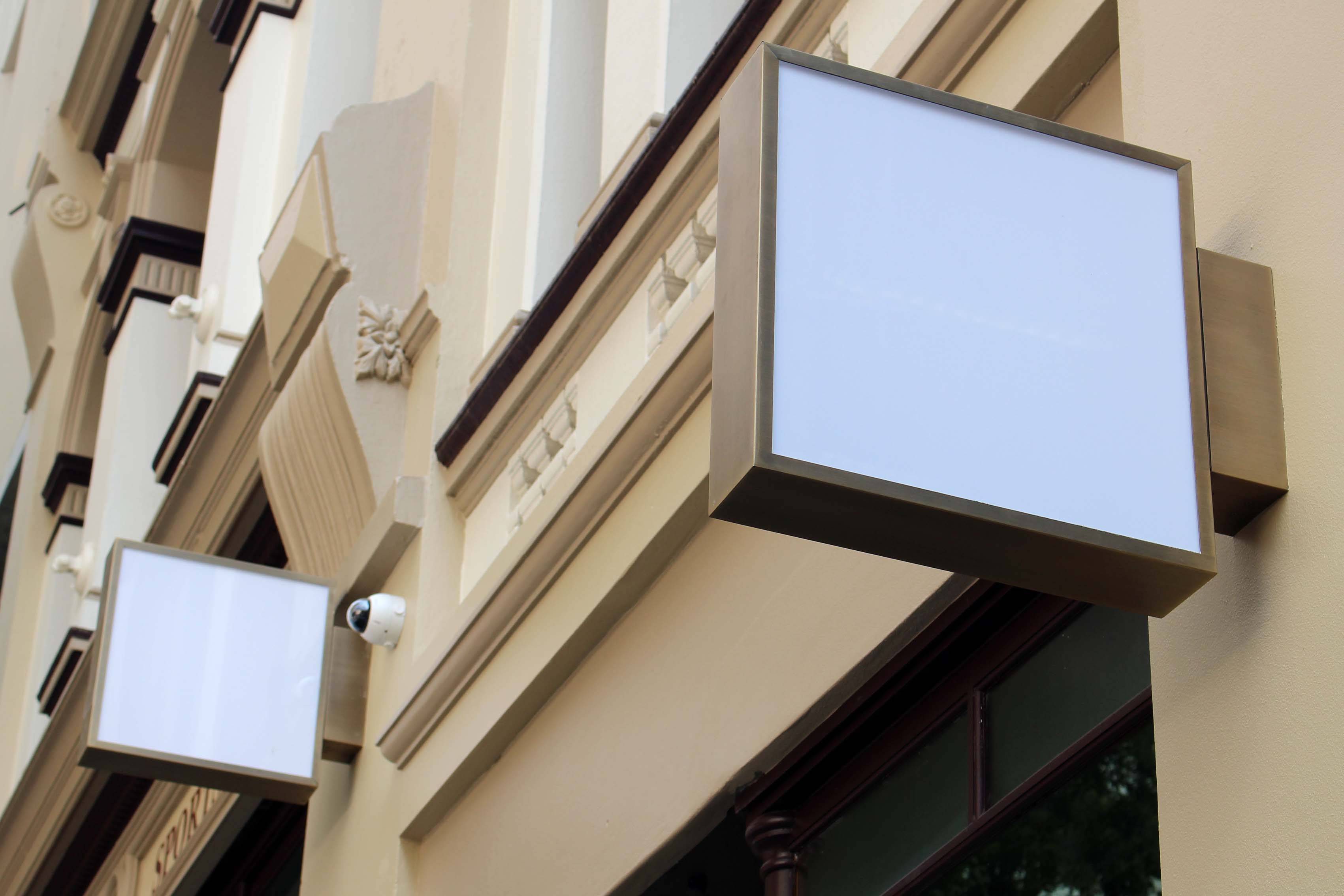 Exterior signage lightboxes with stainless steel fabricated frames mounted on the side of a building.