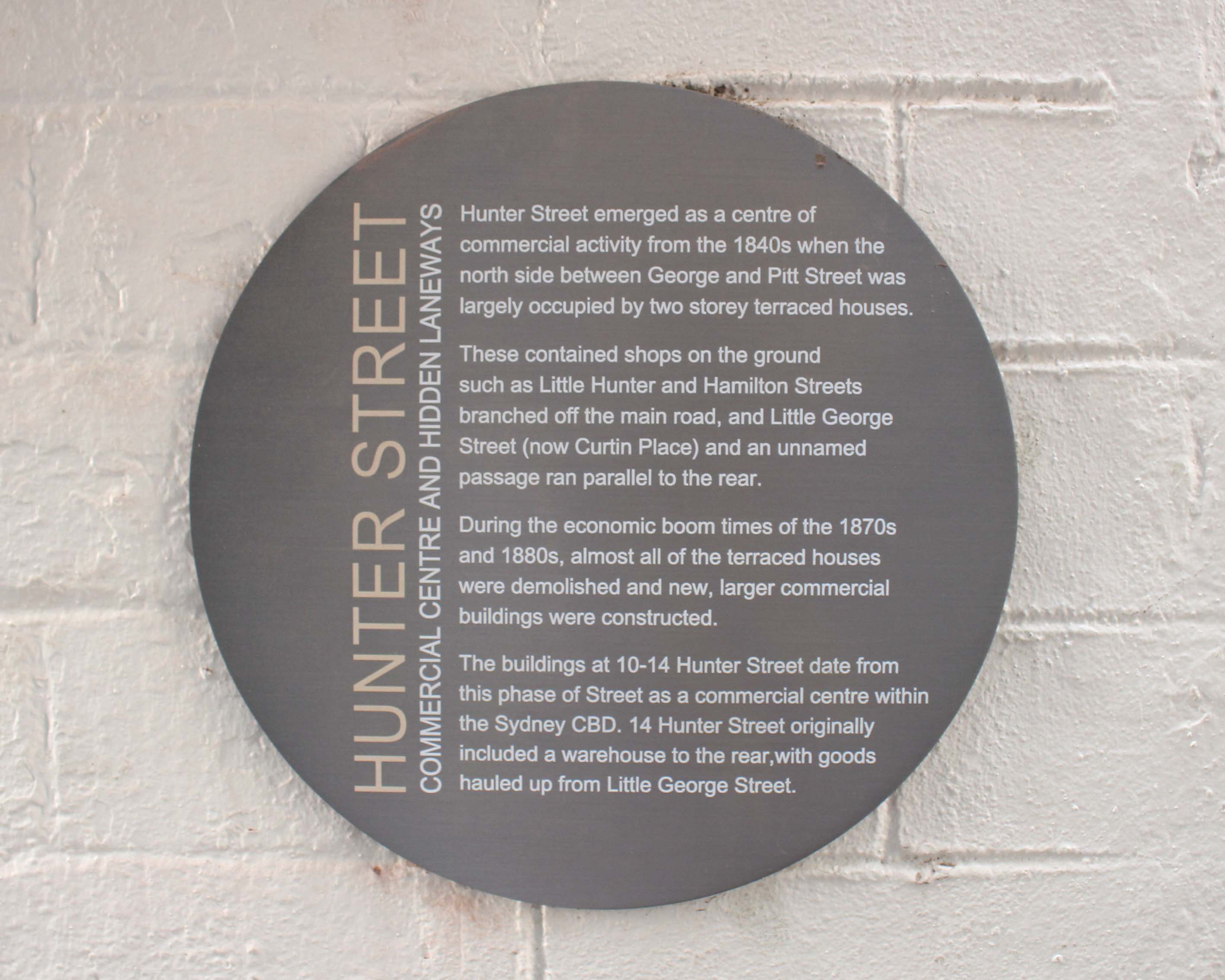 A stainless steel circular external wall plaque digitally printed showing the road map and intersection of George and Hunter Street.