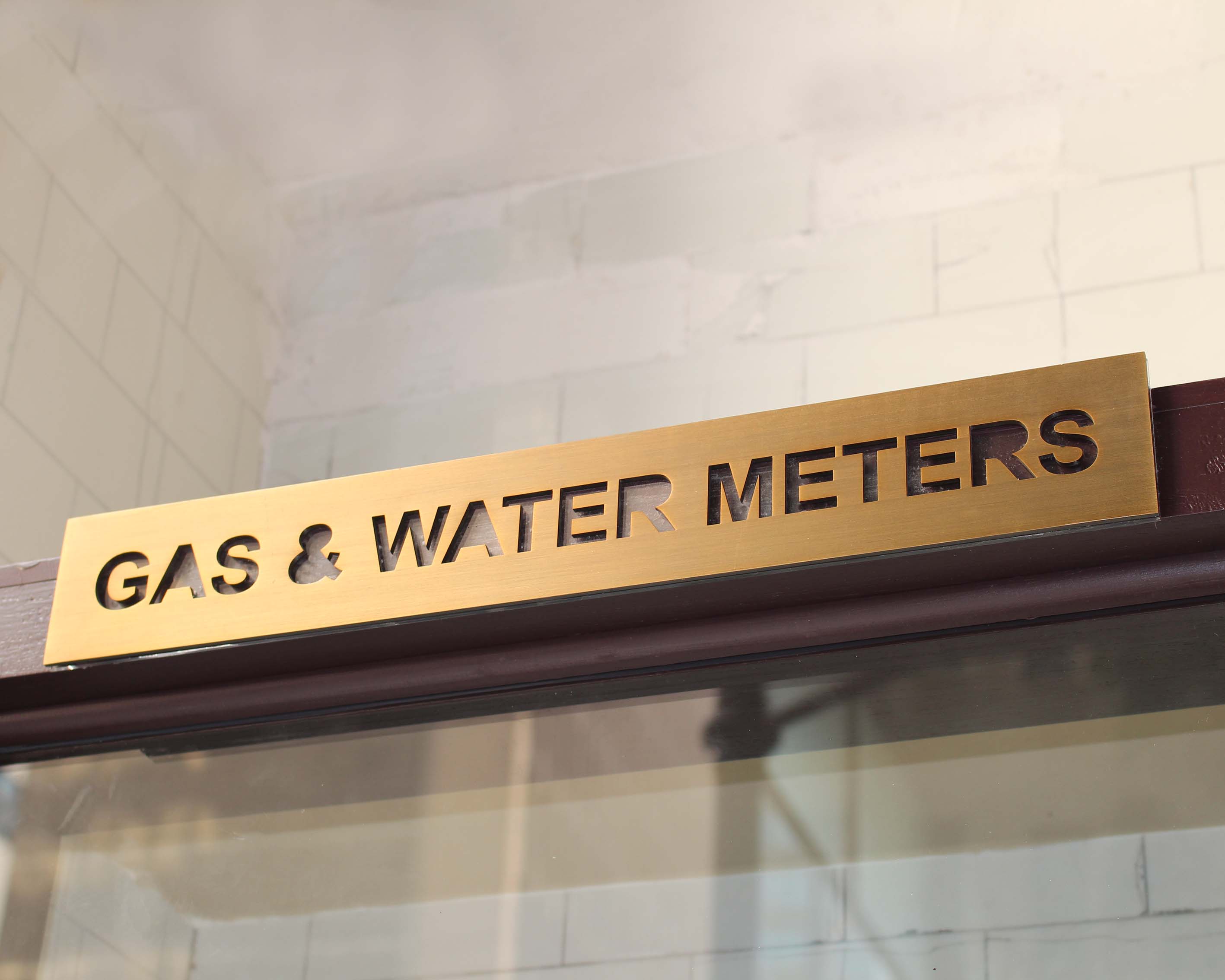 A photo of a brass laser cut gas and water service sign 