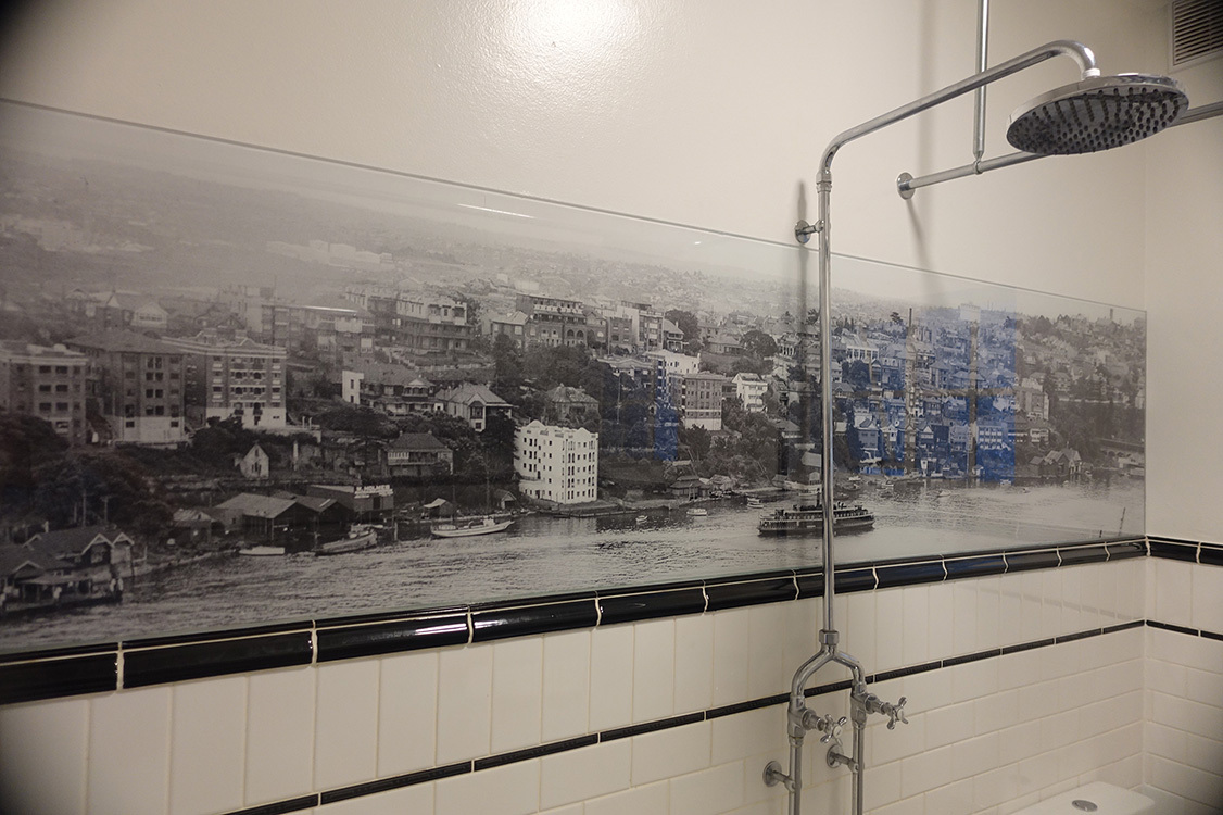 Black and white custom printed shower glass splashback set above white tiles.