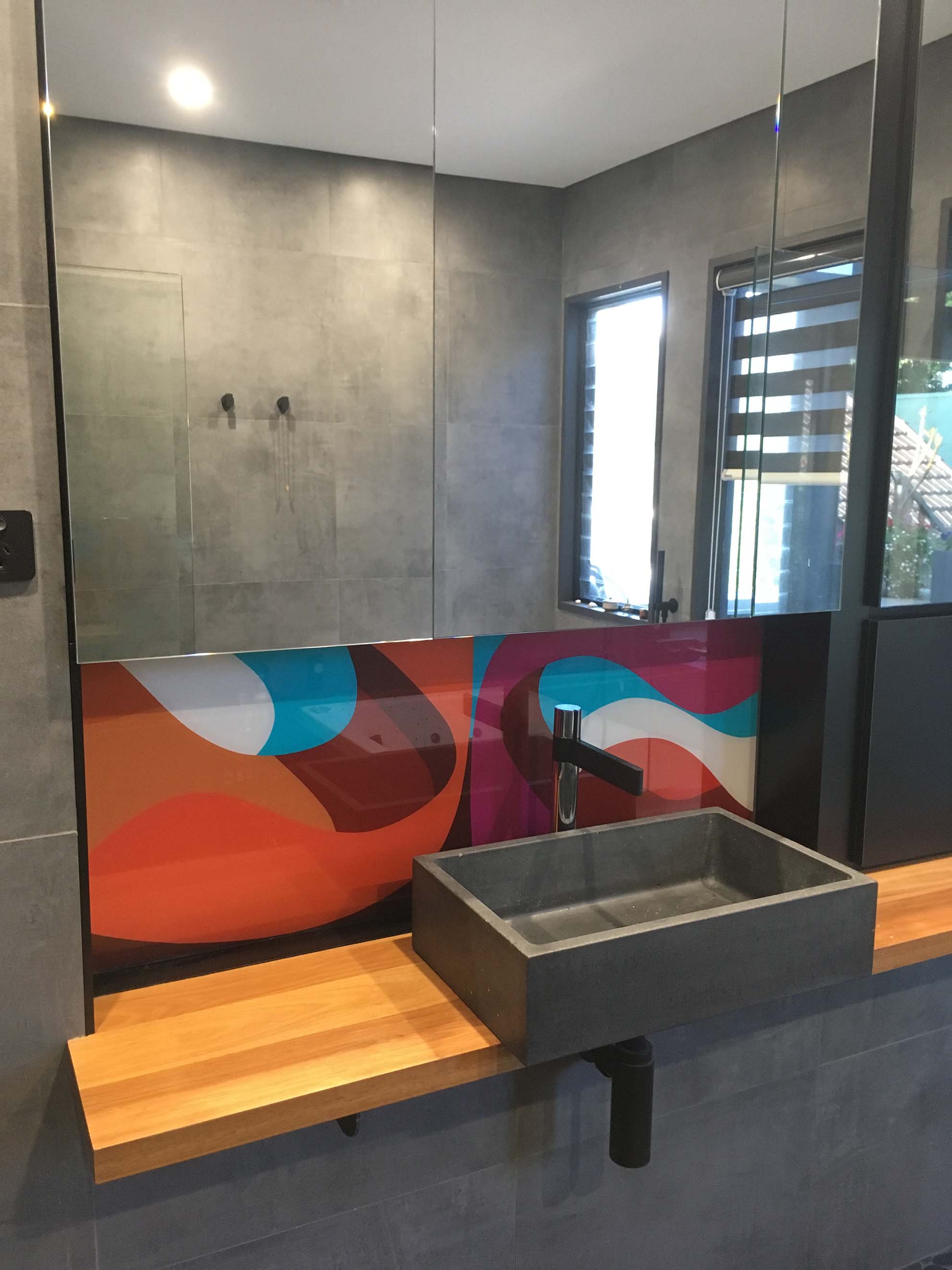 Colourful glass printed splashback behind bathroom sink.