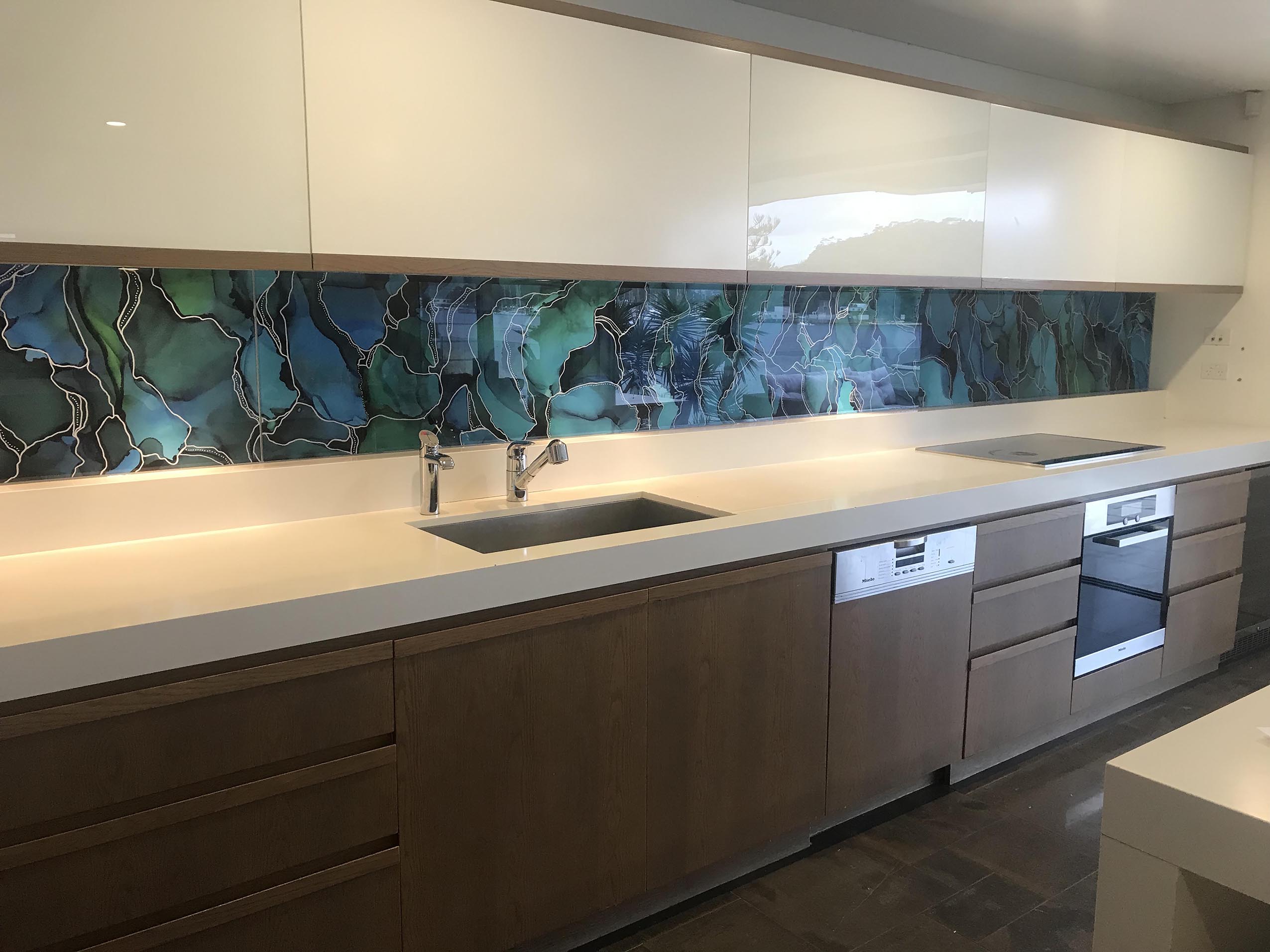Kitchen with a custom printed blue and green glass splashback.