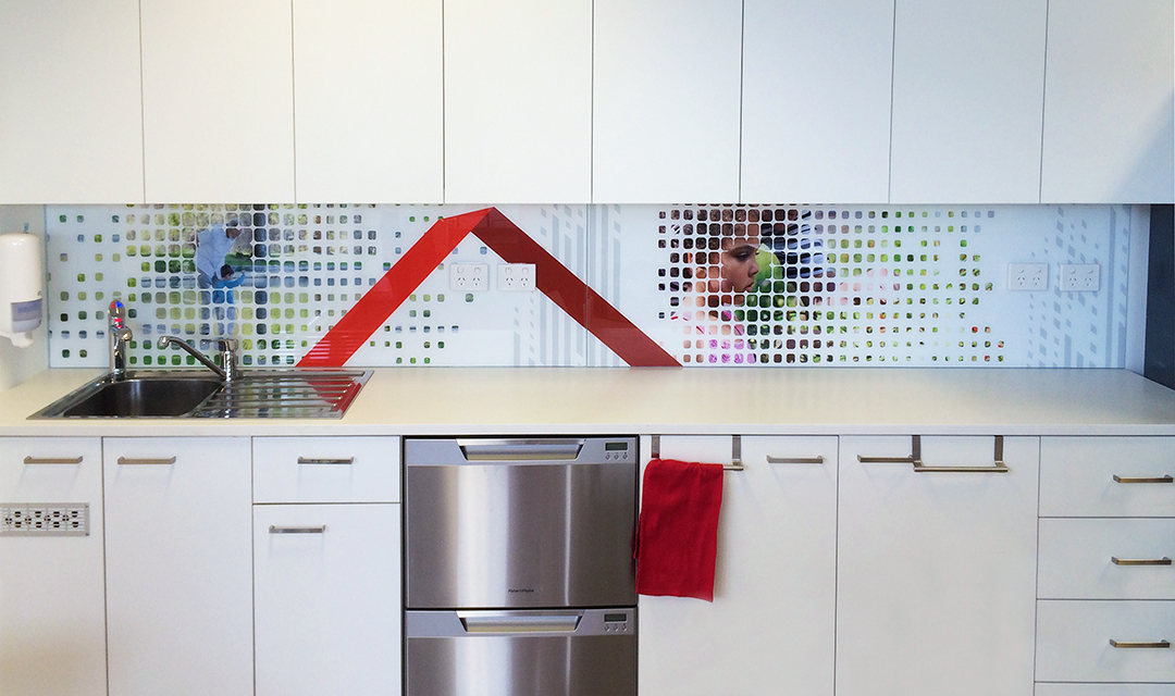Corporate kitchen with a custom printed glass splashback that includes the company logo