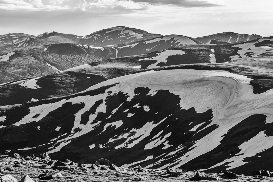 Photo of a mountain range with scattered snow remnants on it