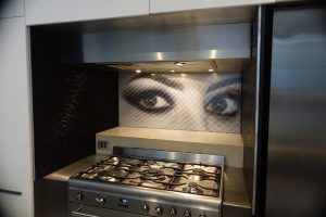 Kitchen featuring a glass splashback with a close up photo of a woman's eyes