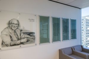 A large pin mounted glass print of Dan Clifton alongside four frosted glass panels with wording.