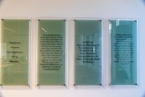 Four frosted glass wall panels mounted with metal stand offs with black text on each.