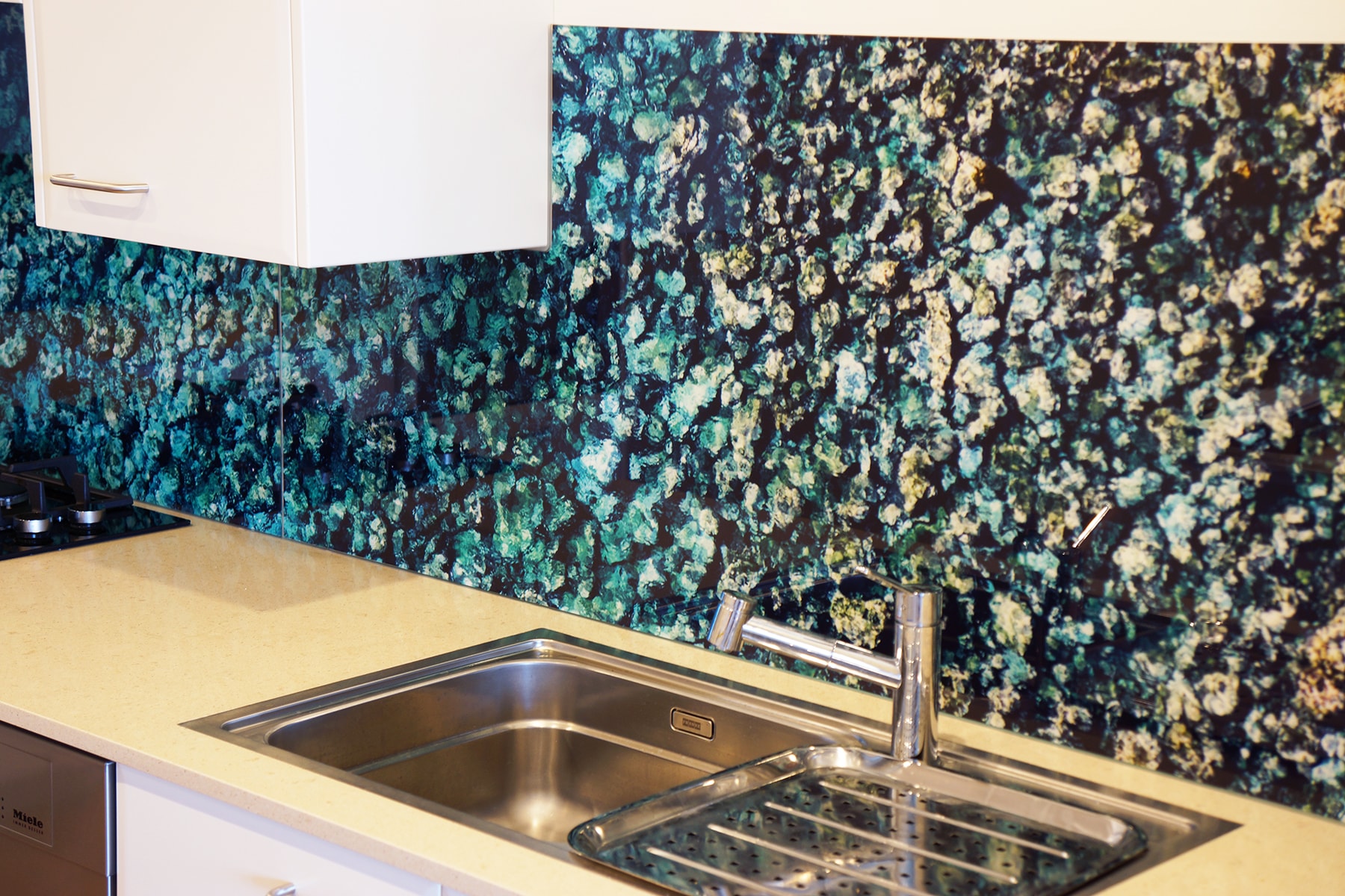 Close up photo of a custom printed glass kitchen splashback with sea water and rock imagery