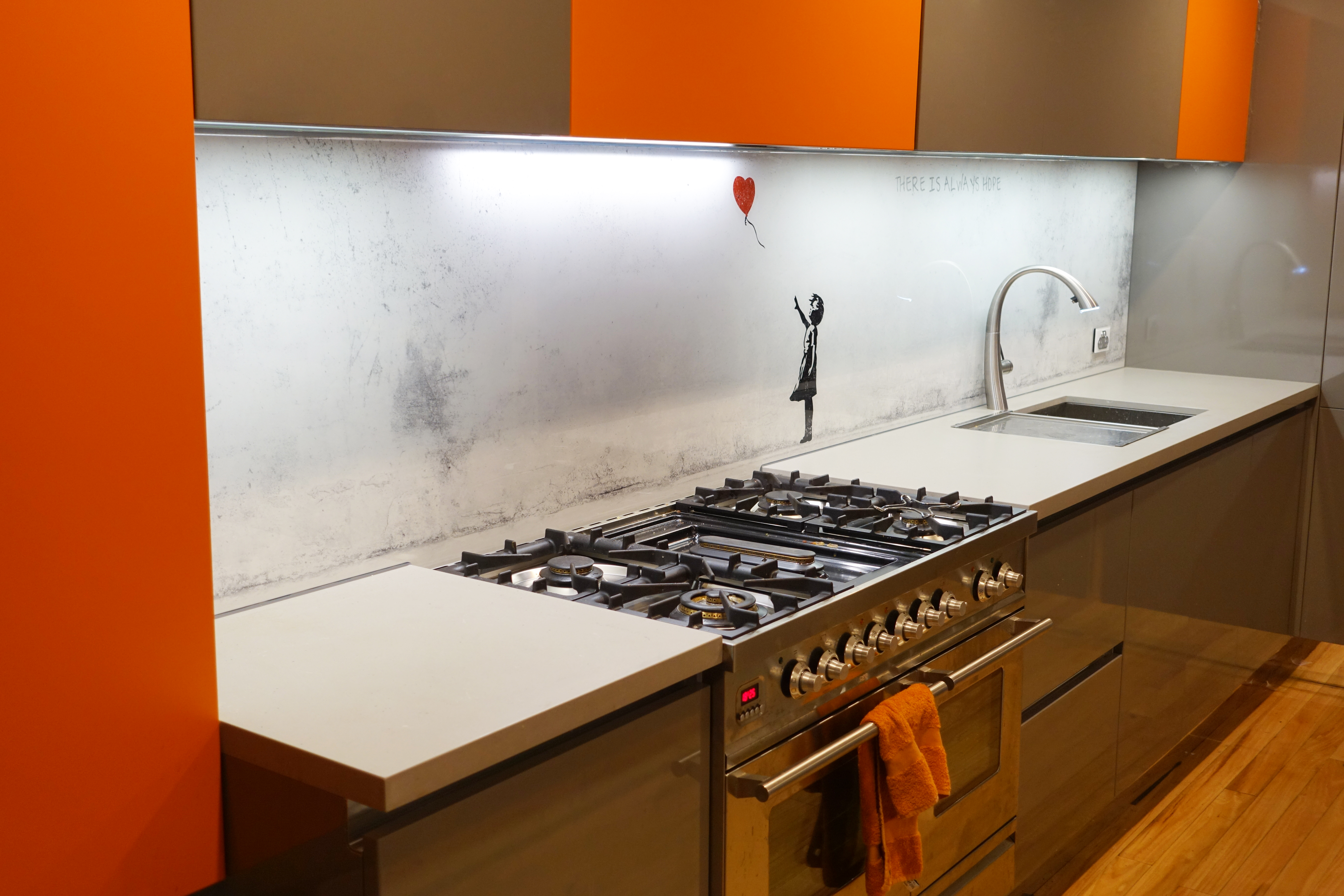Kitchen with a custom glass digitally printed splashback with Banksy's Balloon girl artwork
