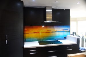 Kitchen with a custom printed glass splashback with an image of a sunset over the sea