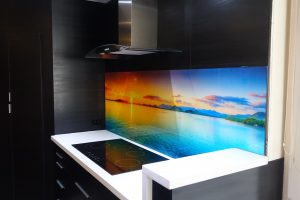 Kitchen with a custom printed glass splashback with a sunset over the ocean image