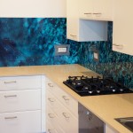 Kitchen with a custom digitally printed glass splashback of sea water and rock imagery
